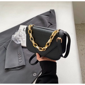 Detail of black faux crocodile skin texture and chunky gold chain strap on small square bag