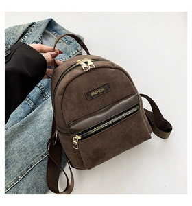 Détail d'un mini sac à dos marron en daim avec étiquette de mode et fermetures éclair dorées