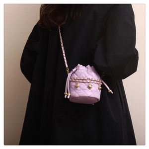 Detail of lavender quilted bucket bag with golden heart charm and chain strap