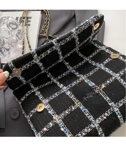Détail du fermoir en métal doré sur un sac bandoulière en tweed noir à carreaux