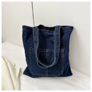 Detailed view of dark blue denim tote bag featuring contrast stitching and front pocket