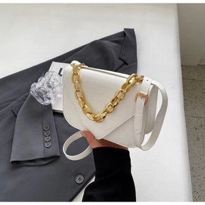 Close-up of white croc-embossed square bag with chunky gold chain handle and V-flap