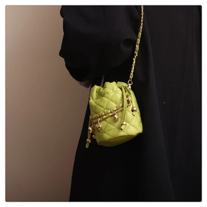 Detail of neon green quilted bucket bag with gold heart charms on a black coat
