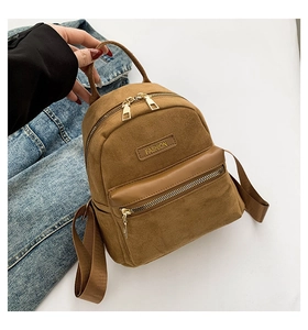 Vue détaillée du mini sac à dos en daim marron avec fermeture éclair dorée et patch