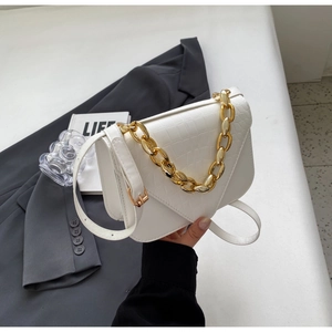 Macro shot of white crocodile embossed mini bag with decorative gold chain handle and strap