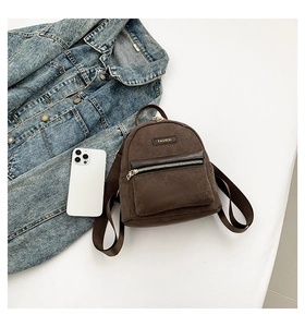 Détail d'un mini sac à dos marron en velours avec zips en métal et étiquette mode