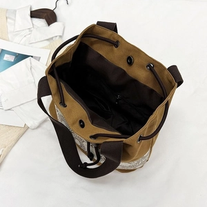 Minimalist brown canvas bucket bag with drawstring closure and wide strap