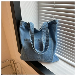 Detailed close-up of blue denim handbag texture and large functional front pocket