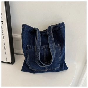 Detail view of deep blue denim tote bag with large front pocket and precise stitching
