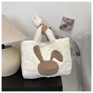 Détail d'un sac cabas en peluche blanche avec écusson lapin et anses en polaire douce