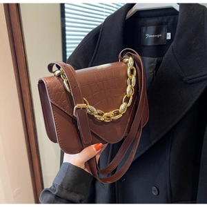 Close-up of brown crocodile pattern leather handbag with decorative gold chain detail