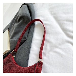 Detailansicht der roten Pailletten-Hobo-Tasche mit Goldbeschlägen auf grauem Anzug