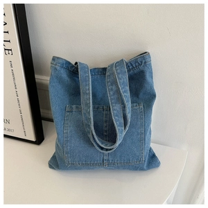 Detailed close-up of blue denim tote bag with large front pocket and double handles