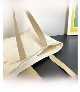 Détail de la fermeture éclair blanche d'un sac cabas en toile avec anses marron
