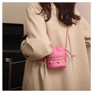 Detailed back view of a pink quilted bucket bag with golden heart charm on a trench coat