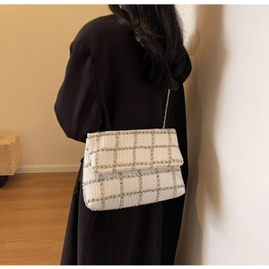 Gros plan sur la texture du sac en tweed crème et bleu avec bandoulière dorée