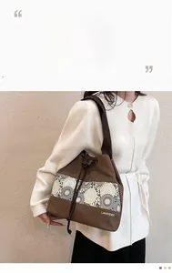 Detail of a brown bucket bag with white lace floral pattern and adjustable shoulder strap