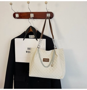 Gros plan du sac cabas matelassé crème avec bandoulière en cuir brun et chaîne argent