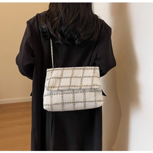 Détail du sac à bandoulière en tweed blanc avec chaîne dorée sur manteau noir