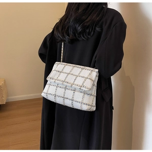 Vue de dos d'un modèle portant un sac à bandoulière en tweed sur un manteau noir élégant