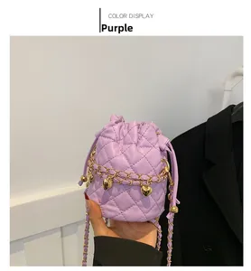 Detail of purple quilted bucket bag with golden heart chain strap and drawstring closure