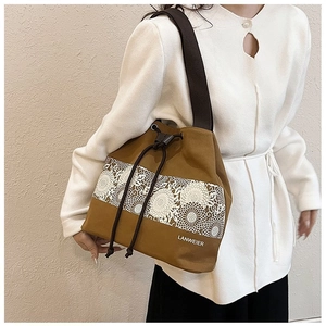 Detail of a brown canvas bucket bag with daisy prints and a wide shoulder strap