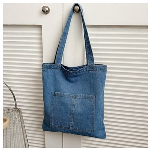 Detail of blue denim tote bag showing symmetric front pockets and high-quality washed texture