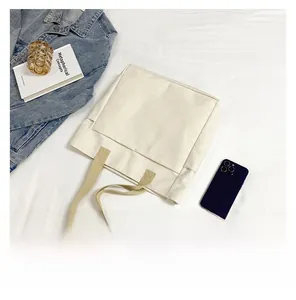 Vue détaillée de la capacité d'un sac cabas en toile beige avec livre et mobile