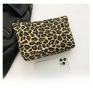 Detailed close-up of leopard print pouch with metal zipper next to a smartphone