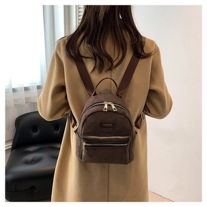 Mini sac à dos en daim marron foncé pour femme porté avec un manteau en laine beige