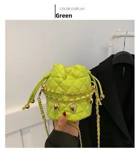 Detail of neon green quilted bucket bag with gold chain strap and heart charm