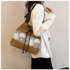 Detail of khaki canvas bucket bag featuring white floral lace and black drawstring strap