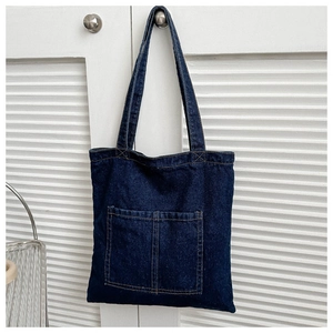 Detail of blue denim tote bag with contrast orange stitching and double front pockets