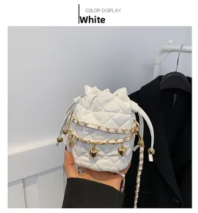 Detail of white quilted bucket bag featuring gold chain and heart-shaped charms detail