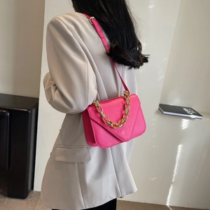 Magenta crossbody bag with stone pattern and gold chain strap worn by a model