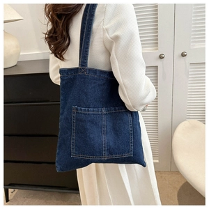 Detail of dark blue denim tote bag featuring contrast stitching and a front pocket