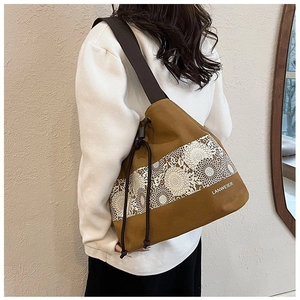 Detailed close-up of brown canvas bucket bag with floral lace pattern and drawstring
