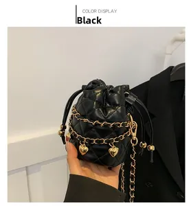 Detail of black quilted bucket bag featuring golden chains and heart shaped metal charms