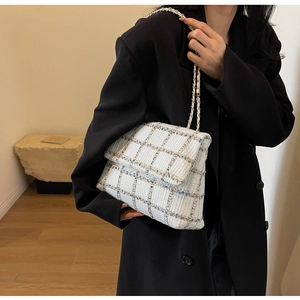 Gros plan du sac en tweed à carreaux bleu clair avec chaîne dorée sur un blazer noir