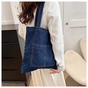 Detailed side view of a large navy denim tote bag with visible stitching and wide shoulder strap