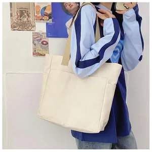 Vue détaillée du sac cabas en toile crème avec poches latérales et sangle kaki à l'épaule