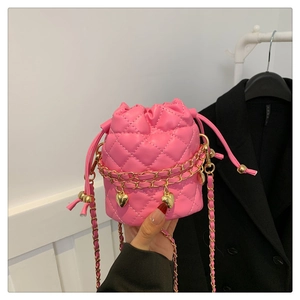 Close-up of pink quilted mini bucket bag with gold chain straps and heart charms