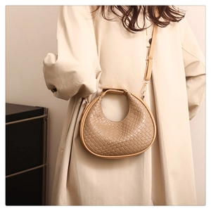 Detail of beige woven crescent bag showing premium leather texture and metallic hooks