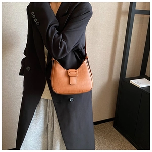 Detail of orange-brown crocodile embossed faux leather on a retro hobo underarm bag