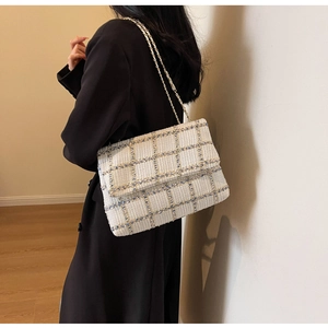 Détail d'un sac à bandoulière en tweed bleu et blanc avec chaîne dorée sur mannequin