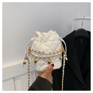 Detail of white quilted bucket bag with gold chain and heart charms on a sleek shoulder strap