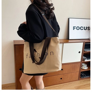 Detail shot of a stylish canvas tote bag worn by a model, showing daily casual commuting style.