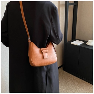 Brown crocodile embossed leather hobo bag worn over a black wool coat, back view