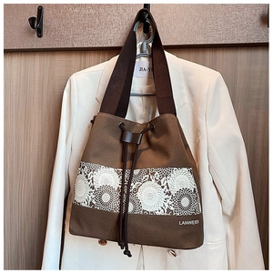 Close-up of brown canvas bucket bag featuring floral lace detail and drawstring