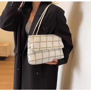 Détail d'un sac bandoulière en tweed blanc à carreaux avec chaîne en cuir sur un mannequin